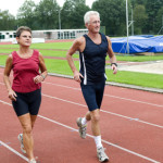 Senior couple running together on a track in a stadium.